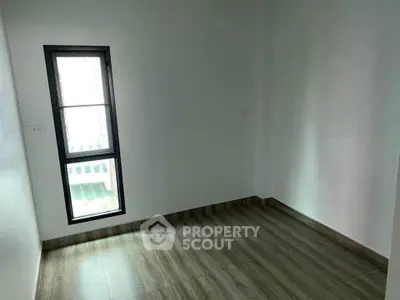 Minimalist empty room with wooden flooring and a window, perfect for customization.
