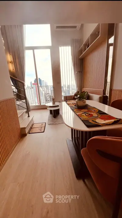 Stylish modern living room with high ceilings and city view, featuring elegant decor and natural light.
