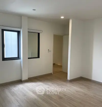 Spacious empty room with wooden flooring and large windows, ideal for customization.