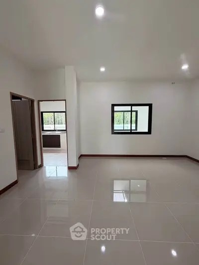 Spacious empty room with large window and glossy tiled floor in modern apartment.