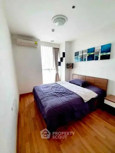 Modern bedroom with wooden flooring and stylish decor in a bright apartment.