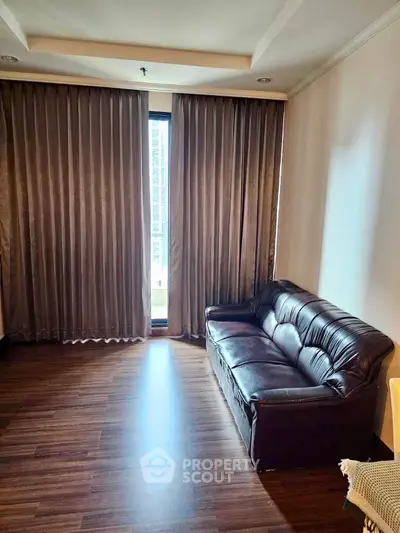 Spacious living room with elegant curtains and a comfortable leather sofa.