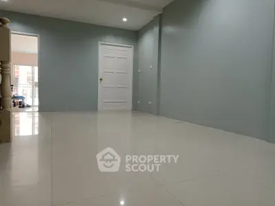 Spacious empty room with glossy tiled flooring and white door, ideal for customization.