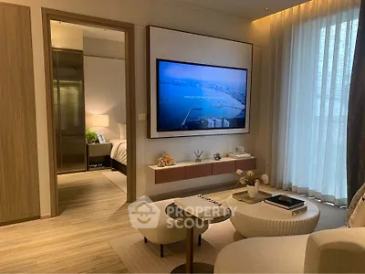 Modern living room with stylish decor and large wall-mounted TV, leading to a cozy bedroom.