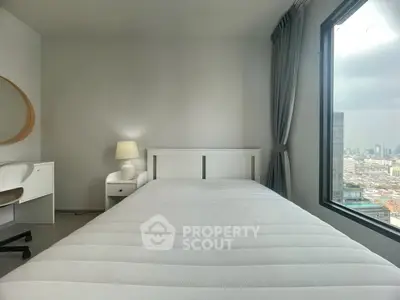Modern bedroom with city view, featuring a cozy bed, stylish desk, and large window for natural light.