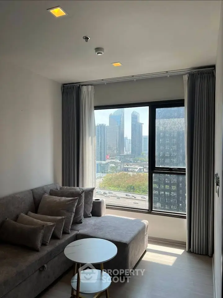 Modern living room with city view, featuring a cozy gray sofa and stylish round coffee table.