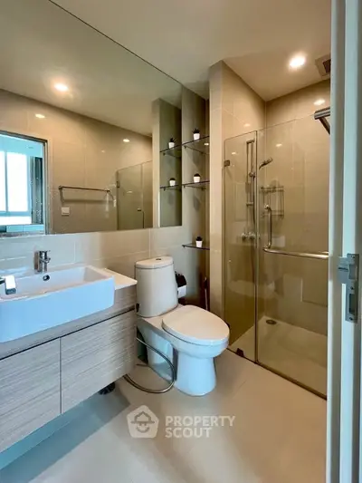 Modern bathroom with glass shower, sleek vanity, and neutral tiles.