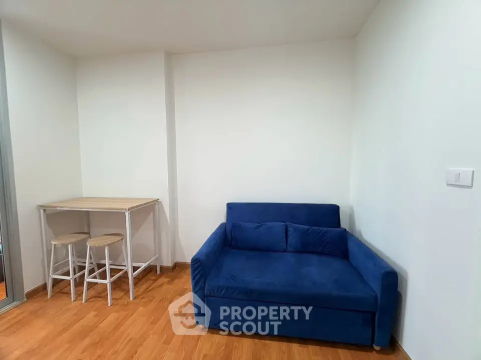 Cozy living room with blue sofa and wooden floor, perfect for relaxation.