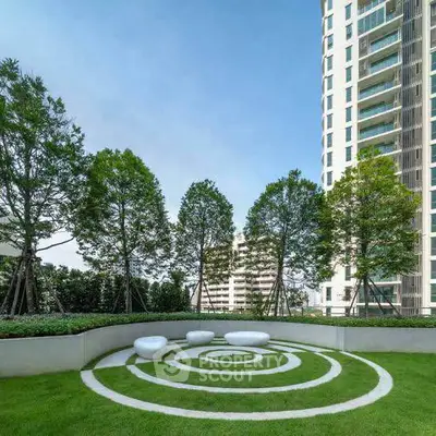 Luxurious garden area with modern seating and lush greenery in upscale residential complex.
