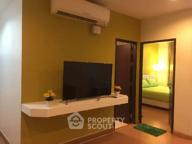 Modern living room with wall-mounted TV and view into cozy bedroom