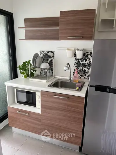 Modern compact kitchen with sleek wooden cabinets and stainless steel appliances.