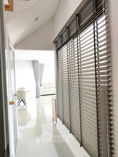 Bright hallway with modern blinds leading to a spacious living area with natural light.