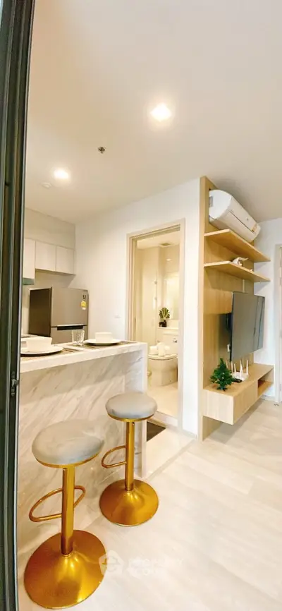 Modern open-layout kitchen with stylish bar stools and cozy living area, perfect for urban living.