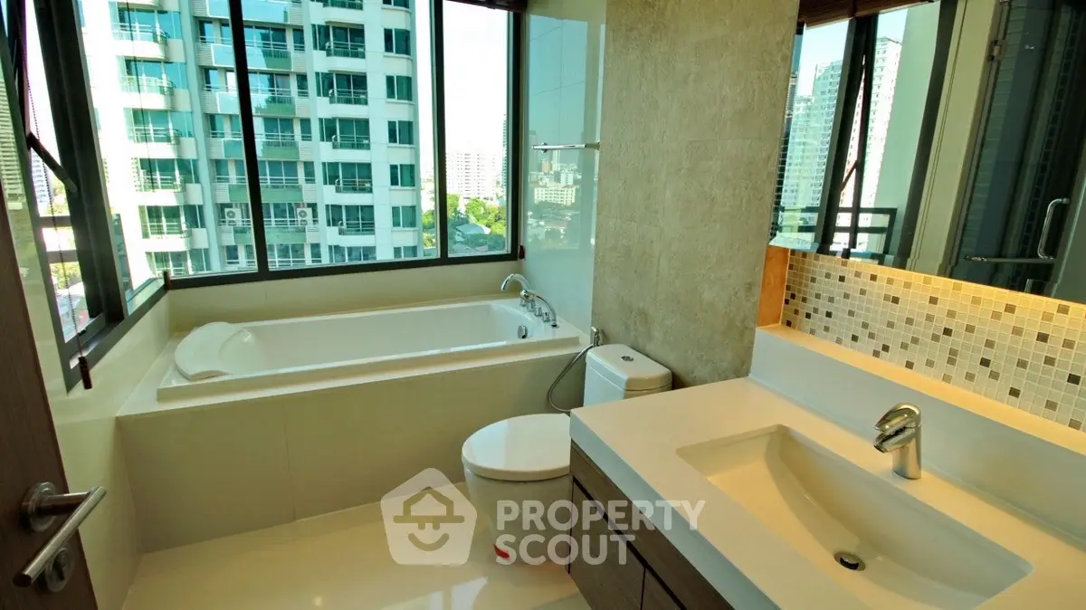 Luxurious bathroom with city view, featuring a bathtub and modern fixtures.