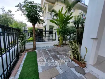 Charming garden view of a modern house with lush greenery and stylish stone pathway.