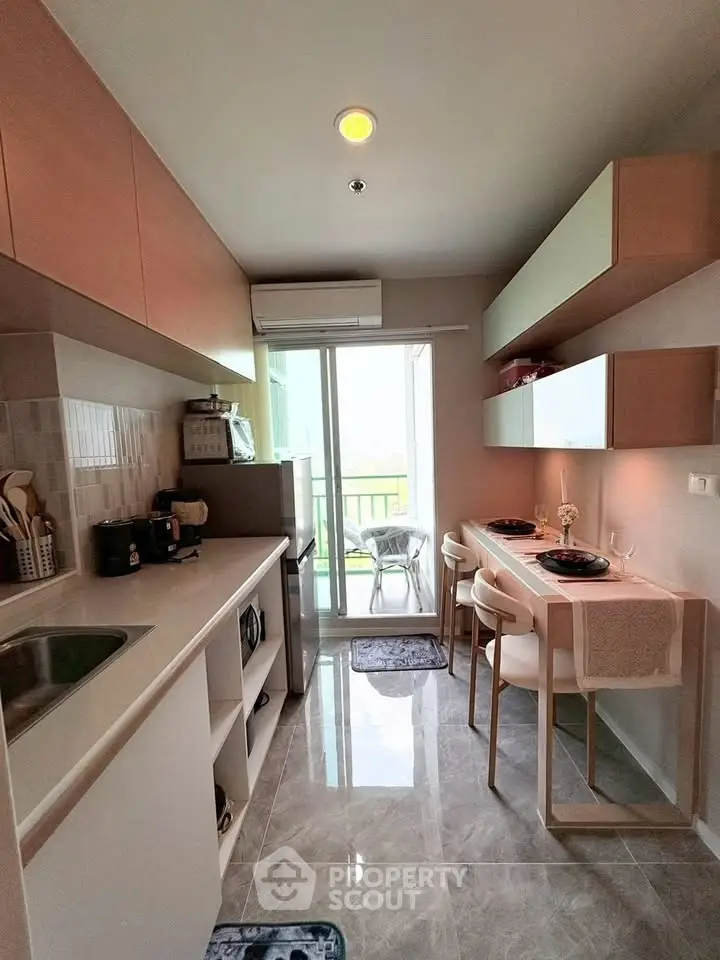 Modern kitchen with sleek cabinetry and breakfast bar, featuring a bright balcony view.