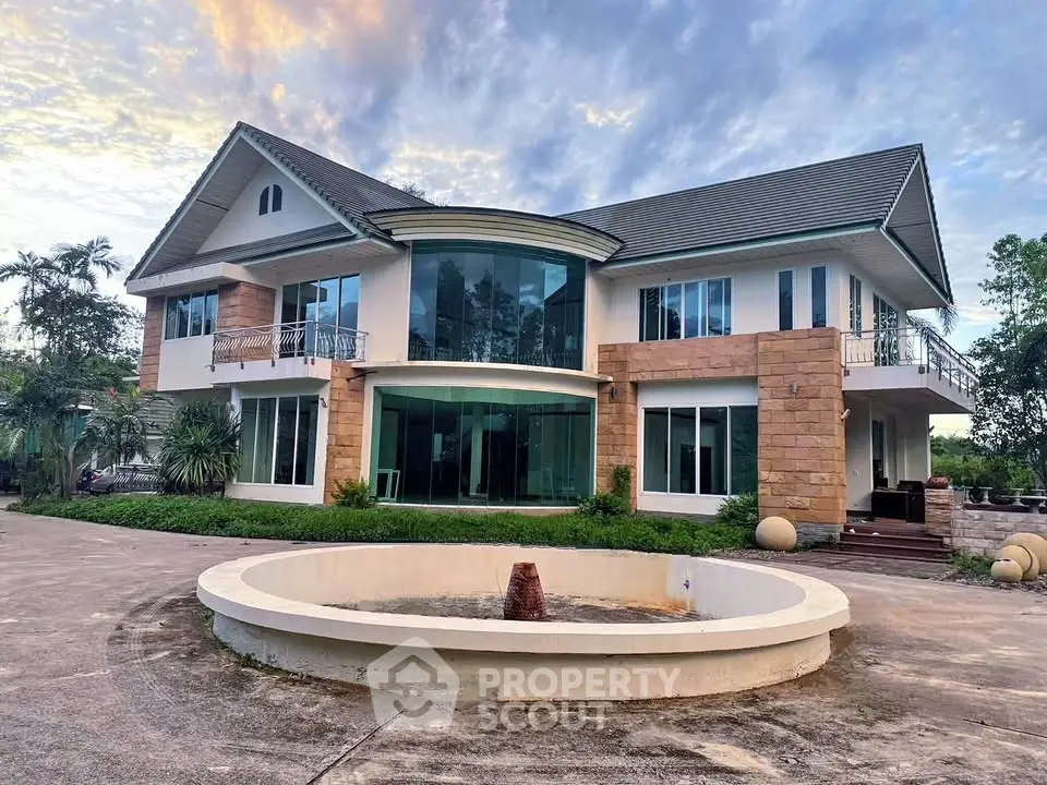 Stunning two-story house with large windows and circular driveway fountain