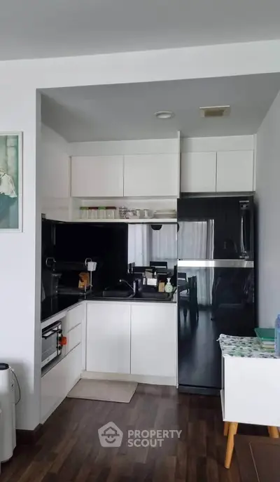 Modern kitchen with sleek black and white design, featuring a spacious fridge and ample storage.