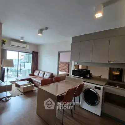 Modern open-plan living room with kitchen, featuring stylish furniture and natural light.