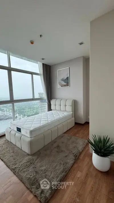 Spacious bedroom with large windows offering stunning city views, featuring a plush bed and modern decor.