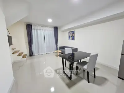 Modern living room with sleek furniture and staircase in a bright, open space.