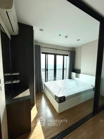 Modern bedroom with large window and wooden flooring in a stylish apartment.