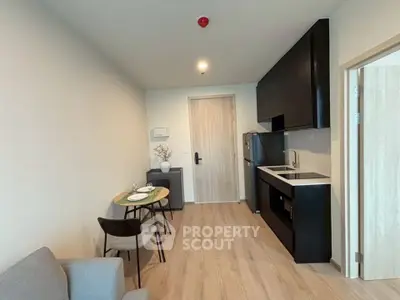 Modern kitchen and dining area with sleek black cabinetry and cozy seating in a stylish apartment.