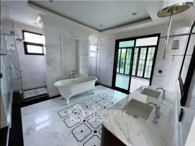 Luxurious bathroom with elegant bathtub and dual sinks, featuring large windows and exquisite tile design.