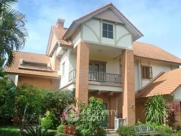 Charming two-story house with red tile roof and lush garden