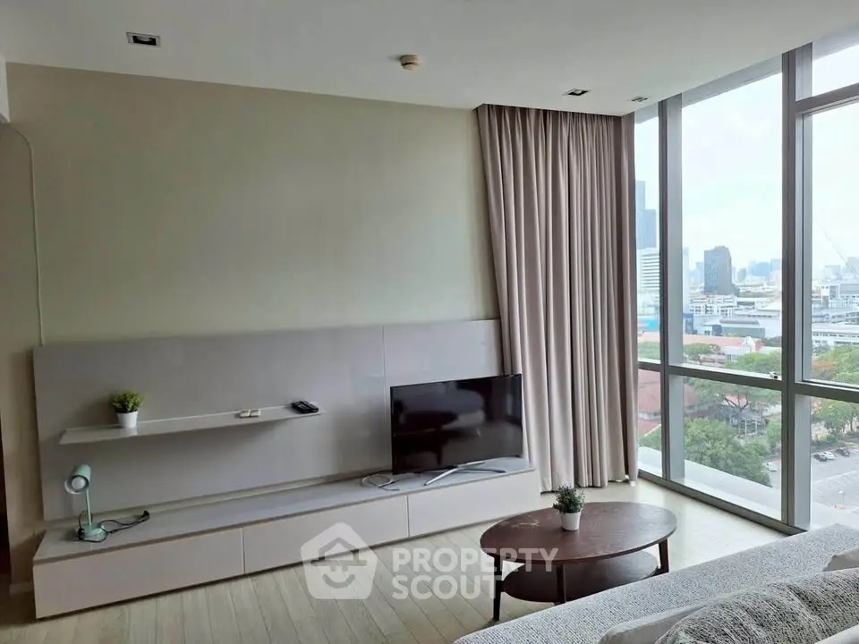 Modern living room with large windows and city view, featuring sleek TV stand and cozy decor.