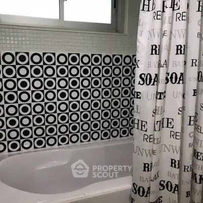 Stylish bathroom with modern circular tile design and bathtub.