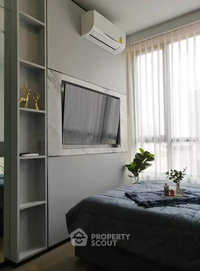 Modern bedroom with large window, wall-mounted TV, and stylish decor