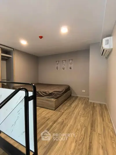 Modern bedroom with wooden flooring and minimalist decor in a stylish apartment.