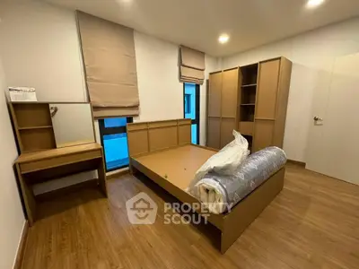 Spacious bedroom with modern wooden furniture and natural light.
