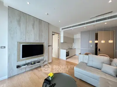 Modern living room with open kitchen, featuring sleek design and cozy seating area.