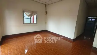 Spacious empty room with tiled floor and window, ready for customization.