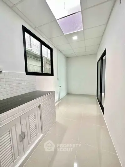 Modern minimalist kitchen with sleek white cabinetry and tiled backsplash.