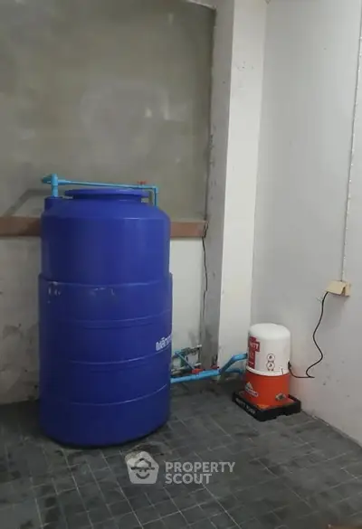 Utility room with blue water tank and plumbing setup in a residential property.