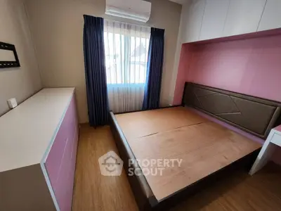 Cozy bedroom with built-in storage and large window for natural light.