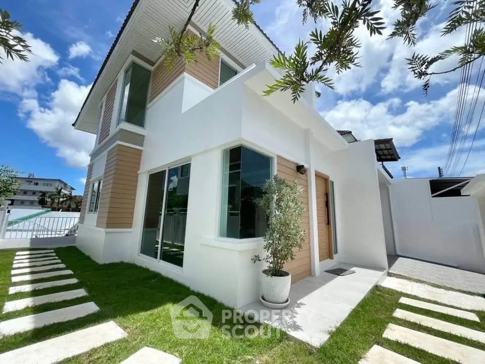 Modern two-story house with sleek design and lush green lawn under a bright blue sky.