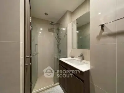 Modern bathroom with glass shower and sleek vanity in contemporary apartment.