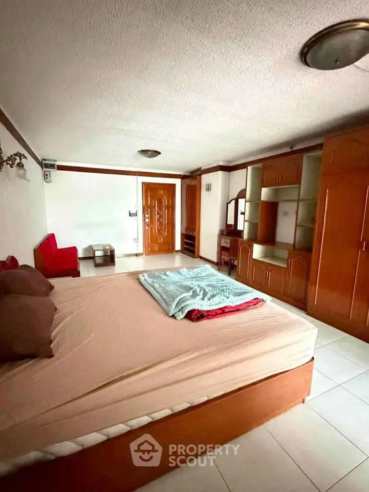 Spacious bedroom with wooden furniture and cozy bed in a well-lit apartment.