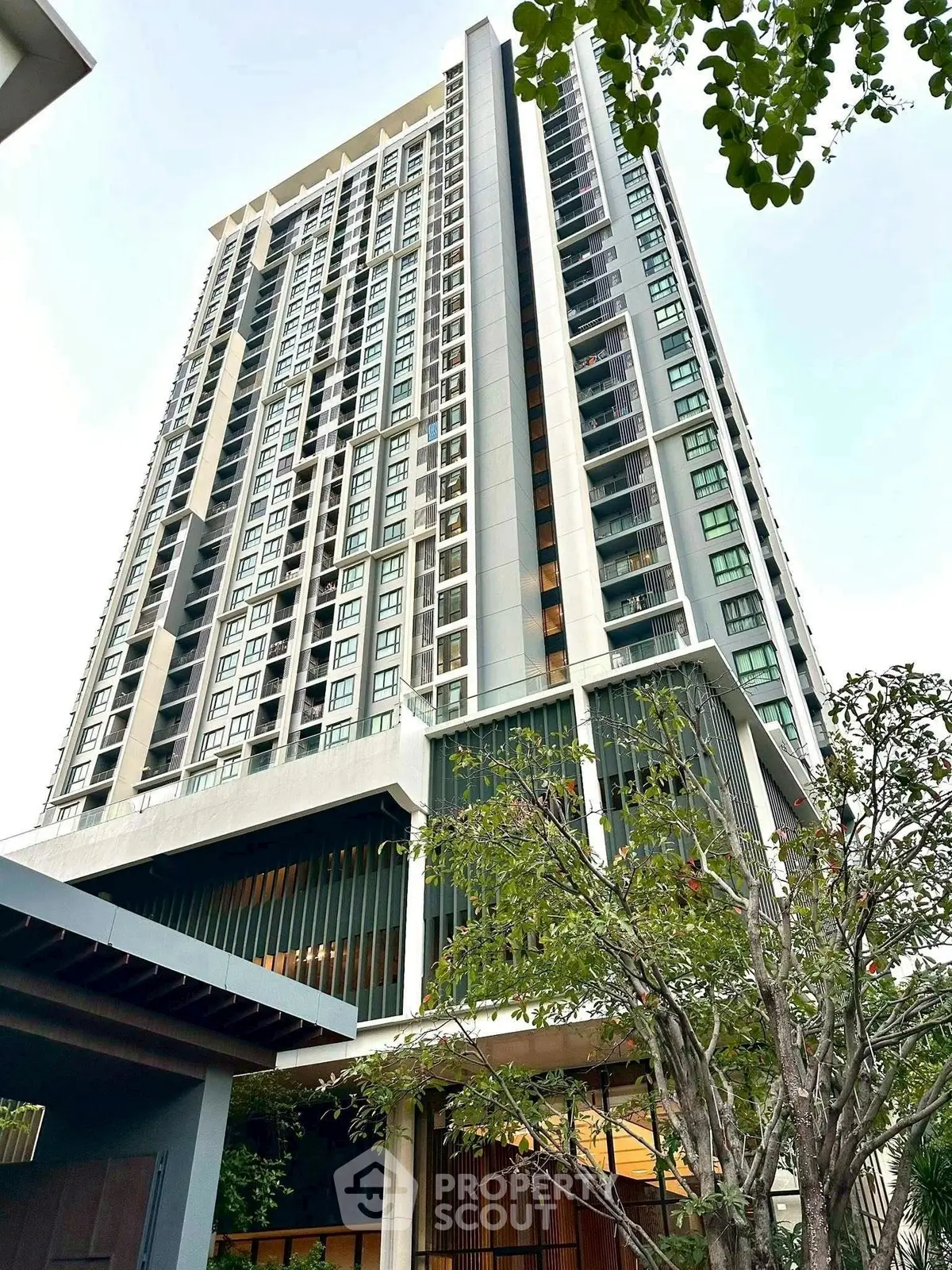 Modern high-rise residential building with lush greenery and sleek architectural design.