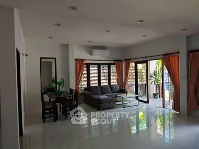 Spacious living room with modern furniture and large windows opening to a garden view.