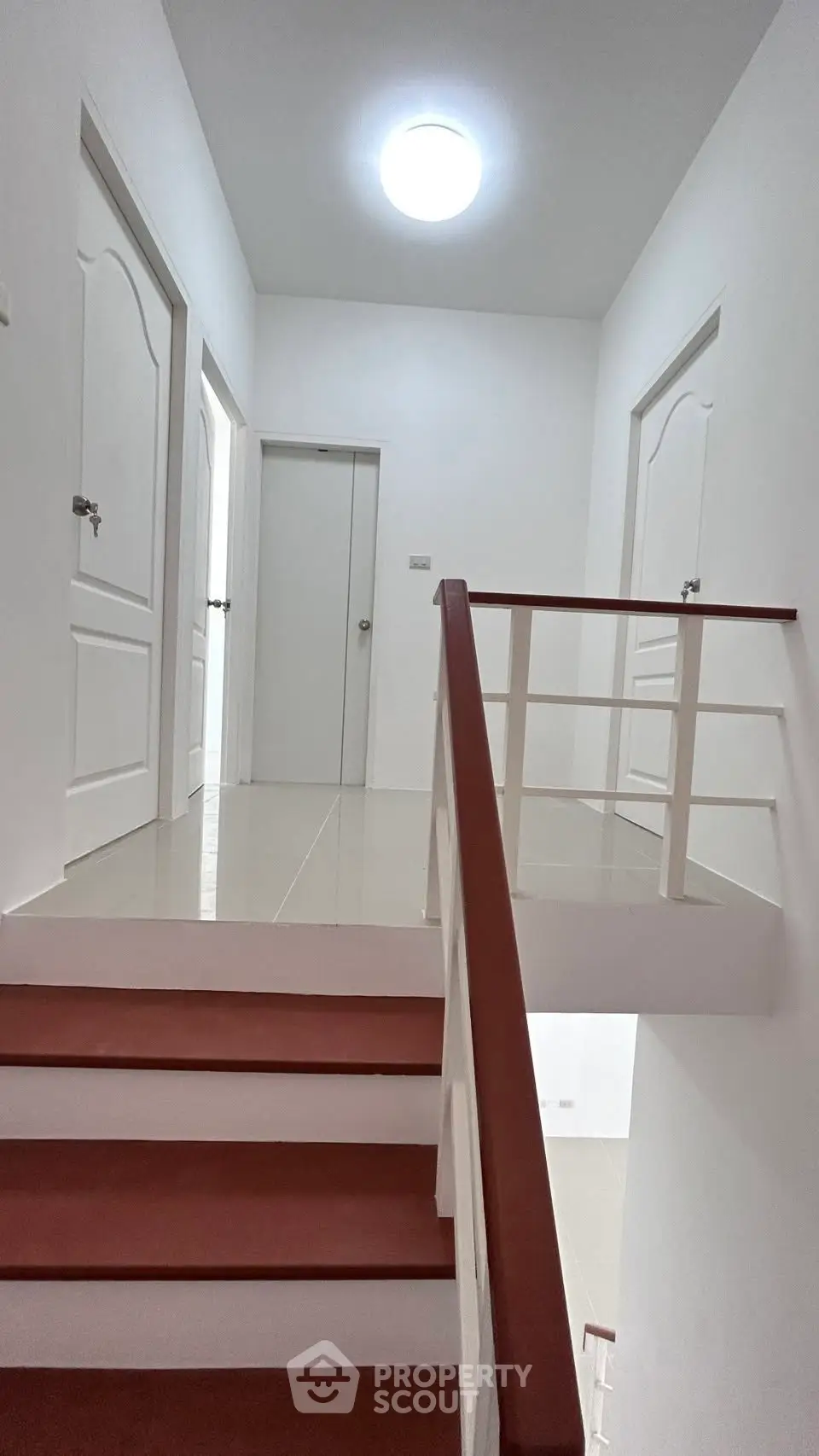 Bright and modern staircase with white walls and wooden handrails in a contemporary home.