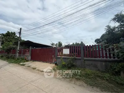 Charming property with red fence and lush greenery, perfect for privacy and tranquility seekers.