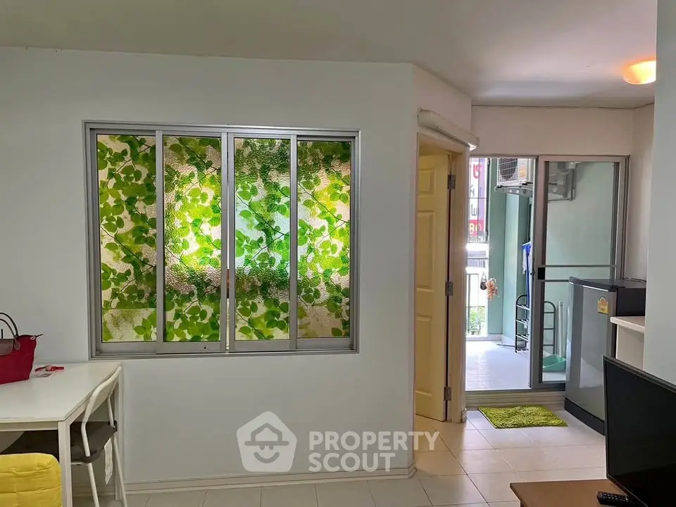 Bright apartment interior with leafy window view and balcony access.