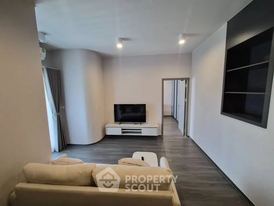 Modern living room with sleek design and neutral tones, featuring a cozy sofa and flat-screen TV.