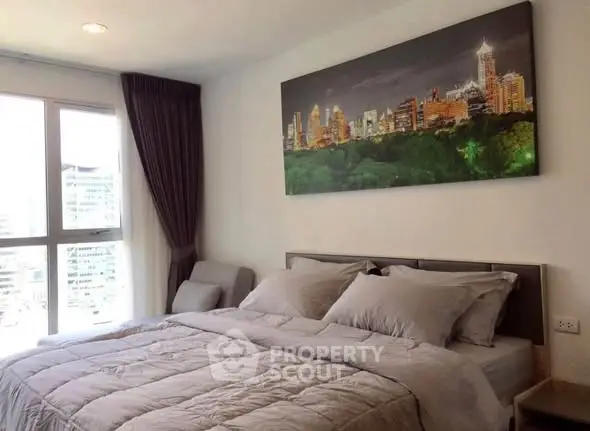 Modern bedroom with cityscape artwork and large window offering natural light.