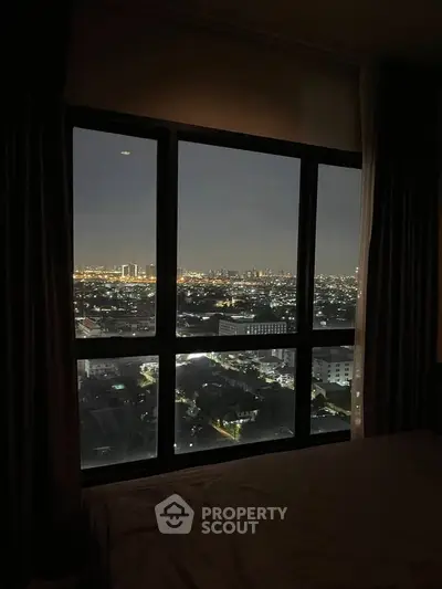 Stunning cityscape view from a high-rise apartment window at night, showcasing vibrant urban lights.